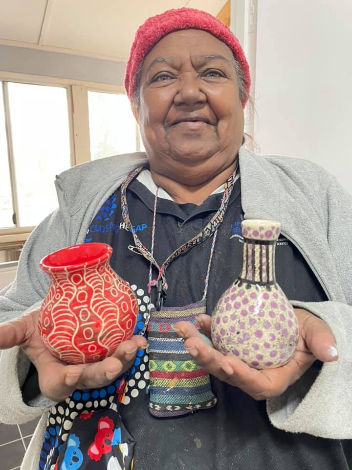 First Nations artist with two pieces of pottery